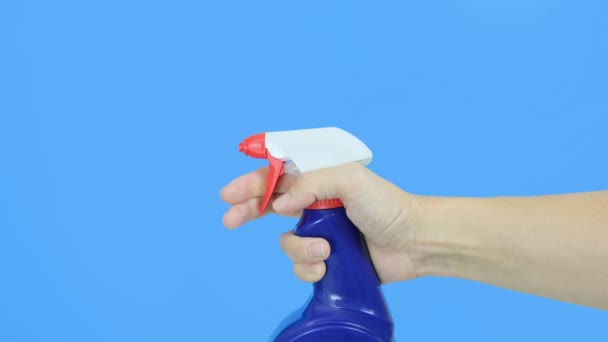 Tangan wanita memegang botol semprotan biru menutup dan menggunakannya, latar belakang biru. Mencuci, membersihkan dan menghapus konsep, menutup — Stok Video
