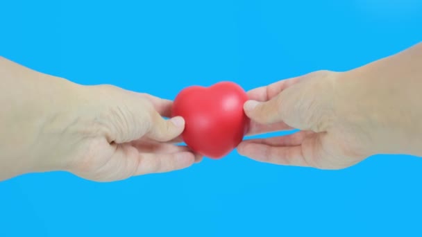 Handen met rood hart tegen blauwe achtergrond, gezondheid, geneeskunde en liefdadigheid concept — Stockvideo