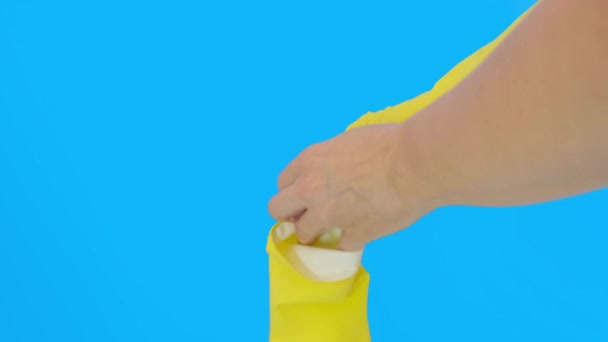 Ręce gospodyni domowej kobiety zakładającej żółte rękawice ochronne z lateksu na niebieskie tło, prace domowe i ochronę podczas sprzątania kuchni i łazienki — Wideo stockowe