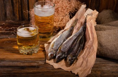 Bardakta bira, tahtadan bir arka planda kurutulmuş balığın yanında.