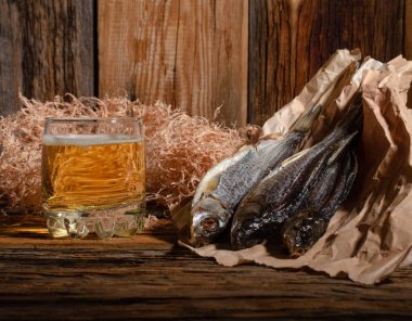 Bardakta bira, tahtadan bir arka planda kurutulmuş balığın yanında.