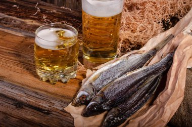 Bardakta bira, tahtadan bir arka planda kurutulmuş balığın yanında.