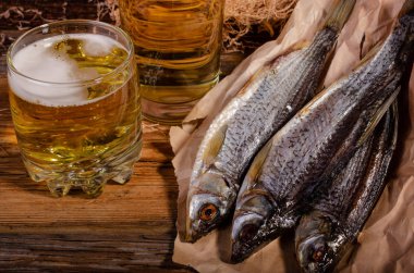 Bardakta bira, tahtadan bir arka planda kurutulmuş balığın yanında.