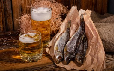 Bardakta bira, tahtadan bir arka planda kurutulmuş balığın yanında.