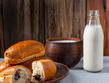 Çikolata dolgulu kahvaltı ruloları ve ahşap bir kırsal arka planda süt, yatay manzara
