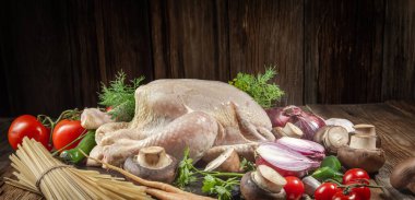 Tavuk yemeği yapmak için taze ürünler. Tavuk, havuç, mantar, soğan, körfez yaprağı, domates, biber, dereotu, maydanoz, makarna, ahşap bir masa üzerinde, yakın plan, kırsal stil ahşap arka plan.