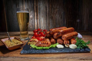 ızgara sosis, kiraz domatesleri, sarımsak, dereotu, bir bardak bira, hardal sosu, ahşap bir masada taze otlar, köy usulü.