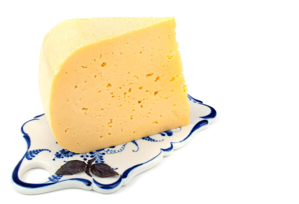 a piece of hard cheese on a ceramic tray, isolated white background, close-up, horizontal view at a sharp angle