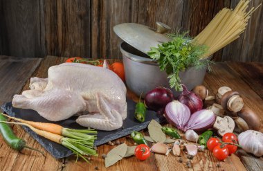 Tavuk yemeği yapmak için taze ürünler. Tavuk, havuç, mantar, soğan, körfez yaprağı, domates, biber, dereotu, maydanoz, makarna, ahşap bir masa üzerinde, yakın plan, kırsal stil ahşap arka plan.