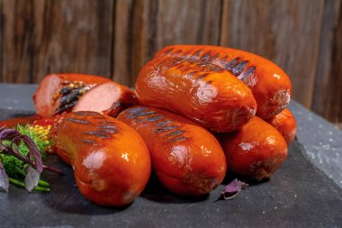 Izgara sosis, hardal tohumu, ketçap, fesleğen ve maydanozu taş tepside, beyaz yalıtılmış arka plan, boş alan