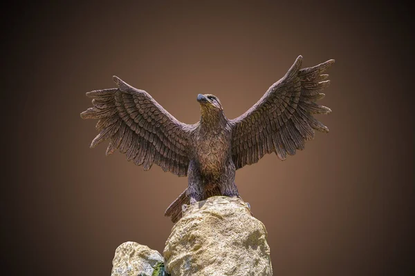 eagle with outstretched wings sitting on a rock, sculpture, dark gradient background, horizontal view, close-up