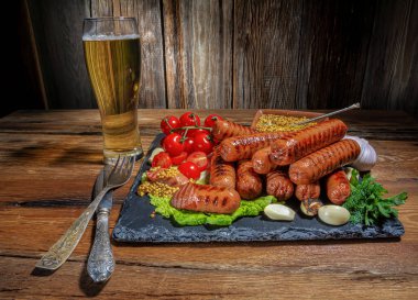 ızgara sosis, kiraz domatesleri, sarımsak, dereotu, bir bardak bira, hardal sosu, ahşap bir masada taze otlar, köy tarzı, yatay görüş.