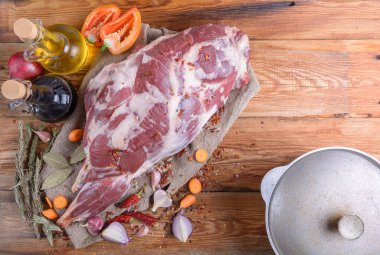 Çuval bezi, soğan, sarımsak, biber, tuz, biberiye ve sebze yağının üzerine işlenmemiş bir koyun bacağı. Yakın plan koyun eti. Taze bir koyun eti. Kırsal tarzda. Yukarıdan manzara. Makro.