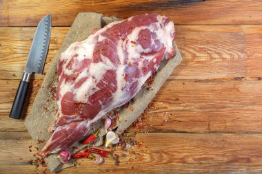 Ahşap bir masanın üzerinde bir kemik üzerinde koyun eti bacağı uzanıyor. Yakın plan koyun eti. Taze koyun eti. En tepeden manzara. Kırsal stil. Makro..