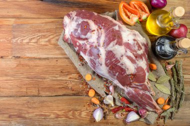 Çuval bezi, soğan, sarımsak, biber, tuz, biberiye ve sebze yağının üzerine işlenmemiş bir koyun bacağı. Yakın plan koyun eti. Taze bir koyun eti. Kırsal tarzda. Yukarıdan manzara. Makro.