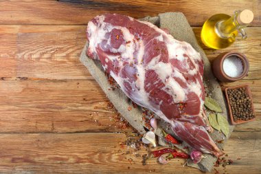 Çuval bezi, soğan, sarımsak, biber, tuz, biberiye ve sebze yağının üzerine işlenmemiş bir koyun bacağı. Yakın plan koyun eti. Taze bir koyun eti. Kırsal tarzda. Yukarıdan manzara. Makro.