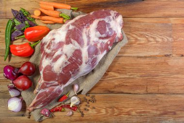 Çuval bezi, soğan, sarımsak, biber, tuz, biberiye ve sebze yağının üzerine işlenmemiş bir koyun bacağı. Yakın plan koyun eti. Taze koyun eti. Yukarıdan görünüşü.