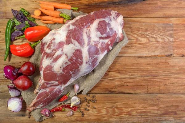Çuval bezi, soğan, sarımsak, biber, tuz, biberiye ve sebze yağının üzerine işlenmemiş bir koyun bacağı. Yakın plan koyun eti. Taze koyun eti. Yukarıdan görünüşü.