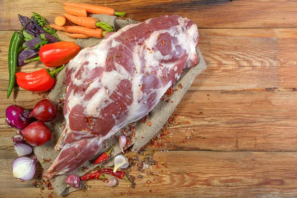 Çuval bezi, soğan, sarımsak, biber, tuz, biberiye ve sebze yağının üzerine işlenmemiş bir koyun bacağı. Yakın plan koyun eti. Taze koyun eti. Yukarıdan görünüşü.