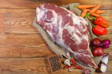 Çuval bezi, soğan, sarımsak, biber, tuz, biberiye ve sebze yağının üzerine işlenmemiş bir koyun bacağı. Yakın plan koyun eti. Taze koyun eti. Yukarıdan görünüşü.