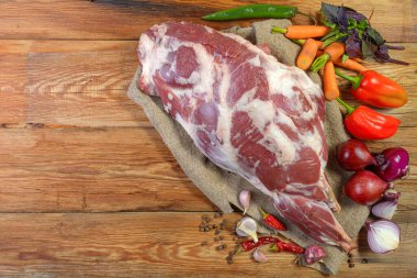 Çuval bezi, soğan, sarımsak, biber, tuz, biberiye ve sebze yağının üzerine işlenmemiş bir koyun bacağı. Yakın plan koyun eti. Taze koyun eti. Yukarıdan görünüşü.