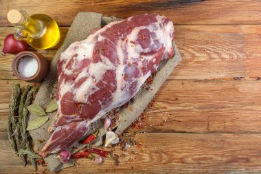 Çuval bezi, soğan, sarımsak, biber, tuz, biberiye ve sebze yağının üzerine işlenmemiş bir koyun bacağı. Yakın plan koyun eti. Taze koyun eti. Yukarıdan görünüşü.