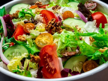 Farklı türde salata, domates, soğan, salatalık ve fındık..