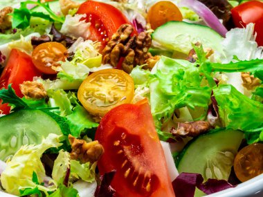 Farklı türde salata, domates, soğan, salatalık ve fındık..