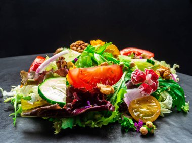 Farklı türde salata, domates, soğan, salatalık ve fındık..