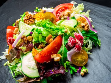 Farklı türde salata, domates, soğan, salatalık ve fındık..