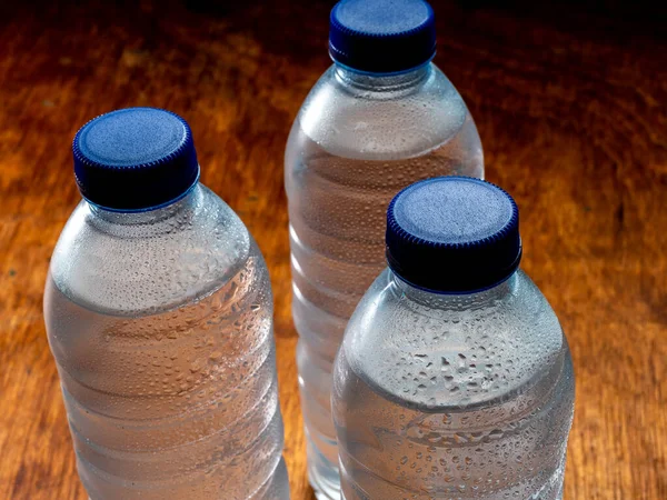 Group of very cold water bottles with blue caps and water drops