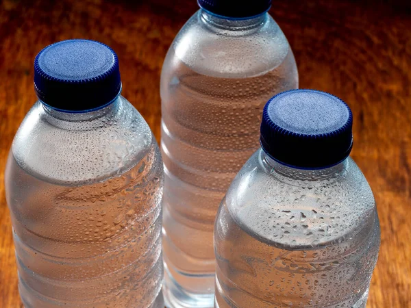 Group of very cold water bottles with blue caps and water drops