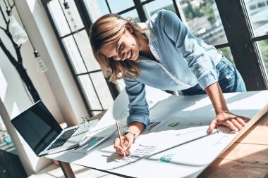gülümseyen kadın masada dizüstü bilgisayar ile planı yazma 