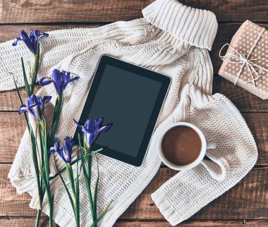 Ahşap masa üzerinde kazak, iris çiçek, kahve fincanı, hediye kutusu ve dijital tablet düz yatıyordu atış