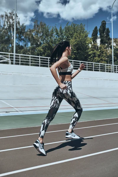 スポーツ陸上競技場で実行されている衣料でブルネットの女性の完全な長さ — ストック写真