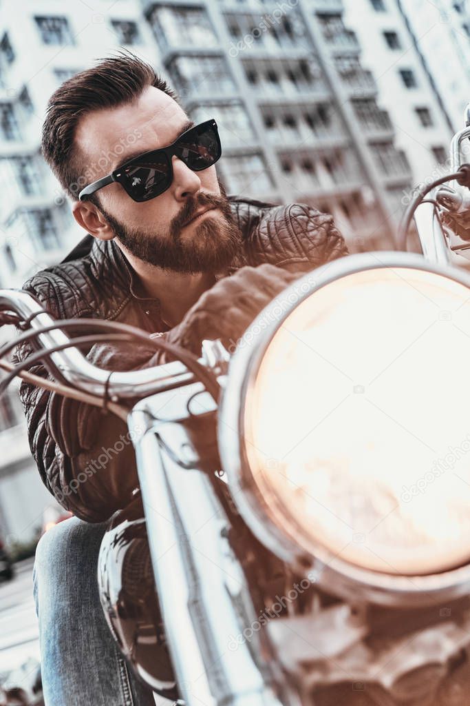 real macho man in leather jacket and sunglasses riding motorbike 