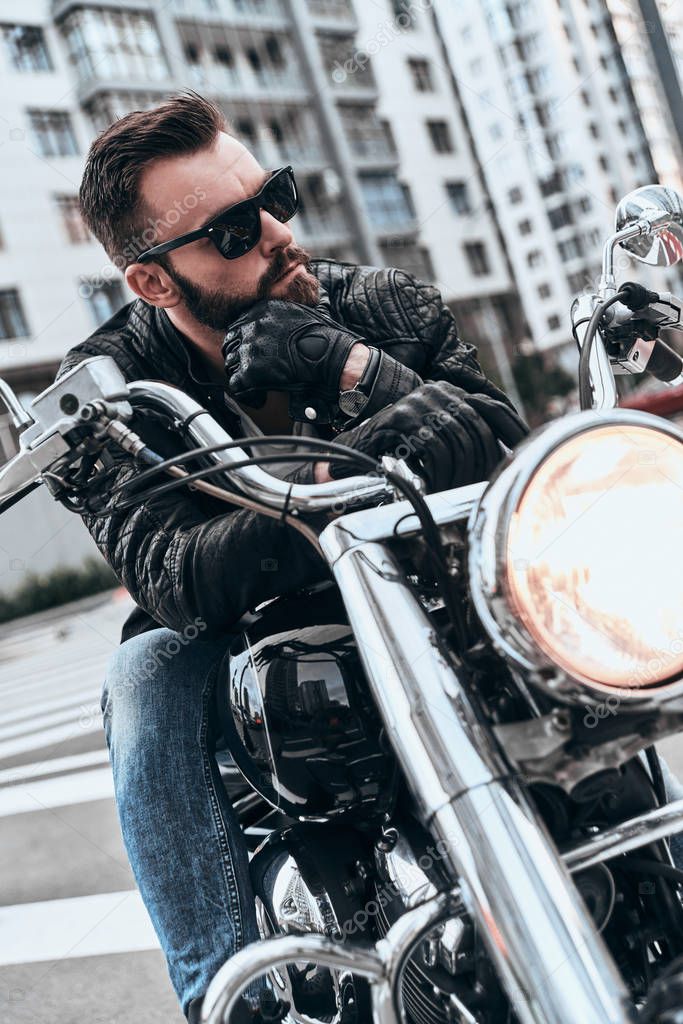 handsome young man in leather jacket and sunglasses sitting on motorbike 