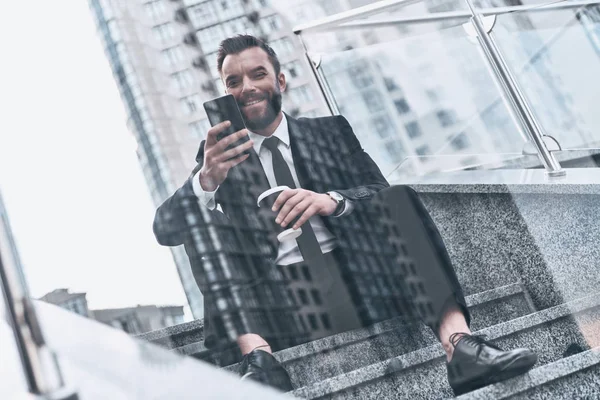 Улыбающийся Бизнесмен Полном Костюме Просматривает Мобильный Телефон Сидит Улице Лестницы — стоковое фото