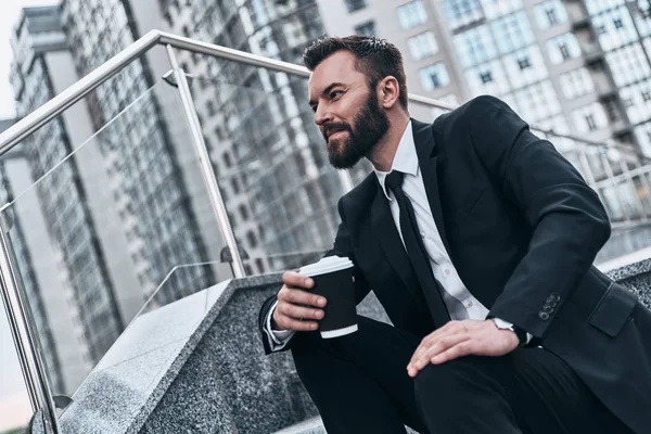 屋外の階段に座って コーヒー カップを保持しているスーツのビジネスマン — ストック写真