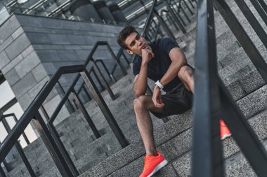 ciddi genç adam uzağa arıyorsunuz ve dışarıda otururken çeneme el tutmak giyim spor
