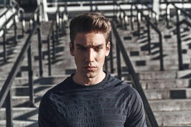 ayakta dışında ve kameraya bakarak ciddi yakışıklı adam portresi