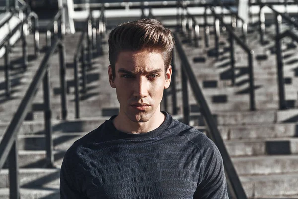 ayakta dışında ve kameraya bakarak ciddi yakışıklı adam portresi