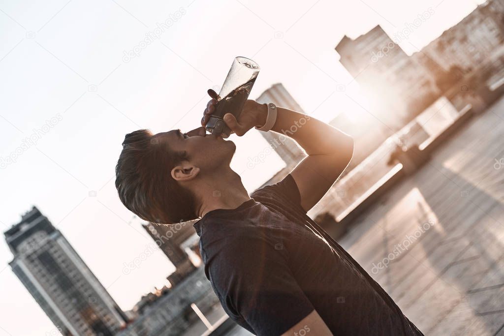 man in drinking water while standing outside