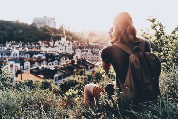 休闲服装中的年轻人的背部视图坐在山上观看城市风景 — 图库照片