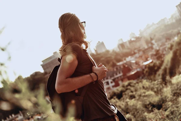 丘屋外に立っている間都市景色眺めてバックパックを持つ男 — ストック写真