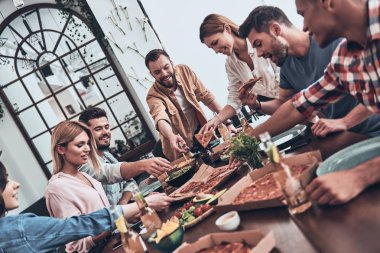 yemek ve akşam yemeği yerken gülümseyen rahat kıyafet içinde gençlerin Grup