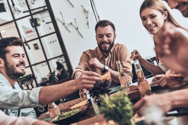 gençlerin yeme ve kapalı bir akşam yemeği yerken gülümseyen casual giyim