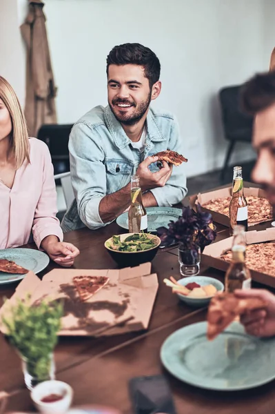 Jovem Bonito Segurando Fatia Pizza Sorrindo Enquanto Desfruta Jantar Com — Fotografia de Stock