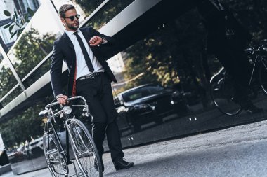 onun bisiklet çekerek ve açık havada yürürken zaman kontrol tam takım yakışıklı genç adam tam uzunlukta