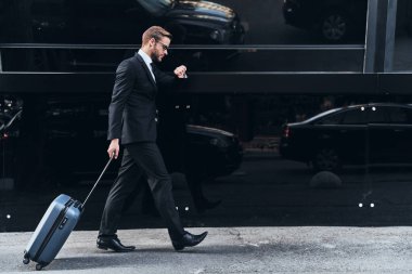 Açık havada yürürken Bagaj çekerek takım elbiseli genç işadamı tam uzunlukta